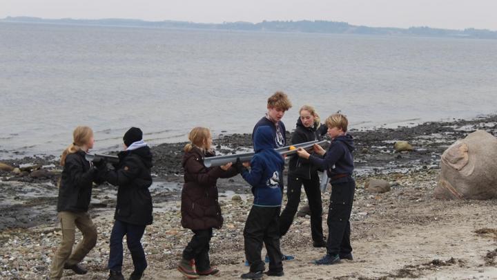 7 spejdere på stranden under et spejderløb løser en post i fællesskab